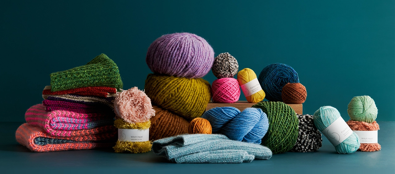 Beautiful yarn in a glorious spectrum of colors with hand-knit pieces, showcasing Purl Soho’s collection of natural fiber yarns and unique knitting patterns.