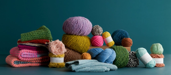 Beautiful yarn in a glorious spectrum of colors with hand-knit pieces, showcasing Purl Soho&rsquo;s collection of natural fiber yarns and unique knitting patterns.