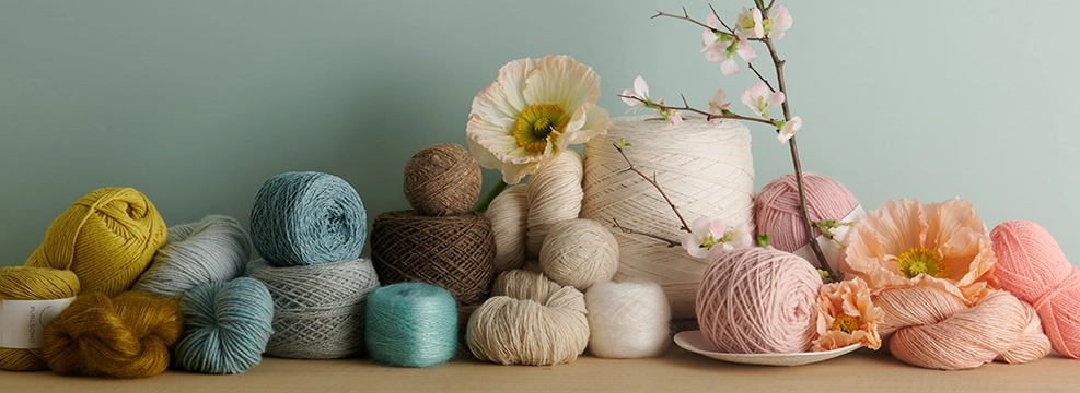 Natural fiber Purl Soho yarns for spring knitting, including Cotton Pure On A Cone, mohair-silk Tussock, and cashmere Nigh DK.